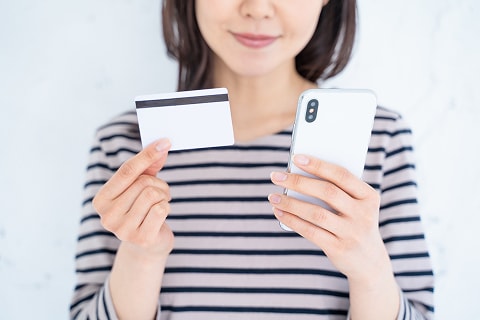 スマートフォンとクレジットカードを持つ女性